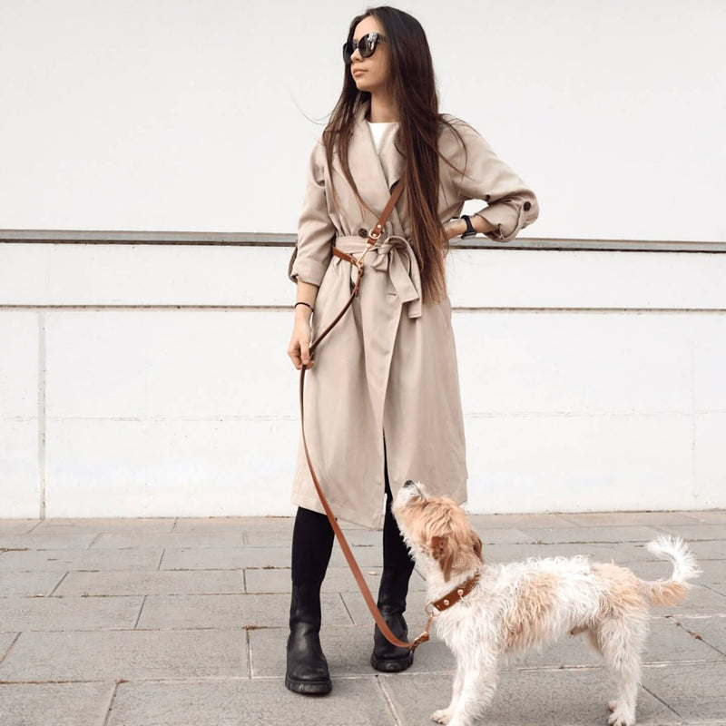 dog-leash-branni-multifunctional-infinity-leashes-cognac-leather-gold-detail-lifestyle-image-human-wearing-assembled-attached-to-dog-collar-standing-the-worthy-bone